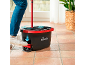 Person using a red mop and black bucket with a foot pedal on a tiled floor.