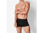 Shirtless man in black boxer briefs, arm crossed.