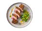 Sliced beef steak with sauce and salad on a plate.