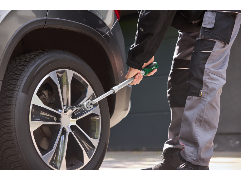 Man tightening car wheel bolts with a torque wrench.