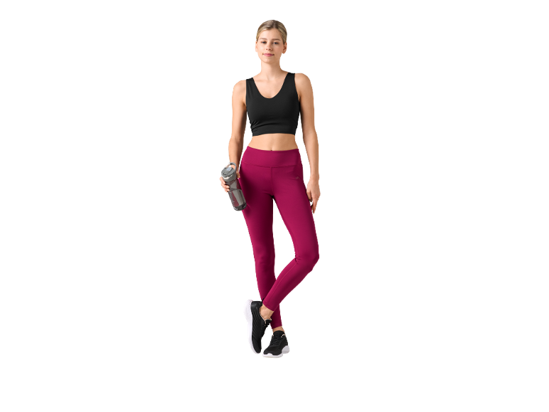 Woman in black sports top and burgundy leggings holding a water bottle.
