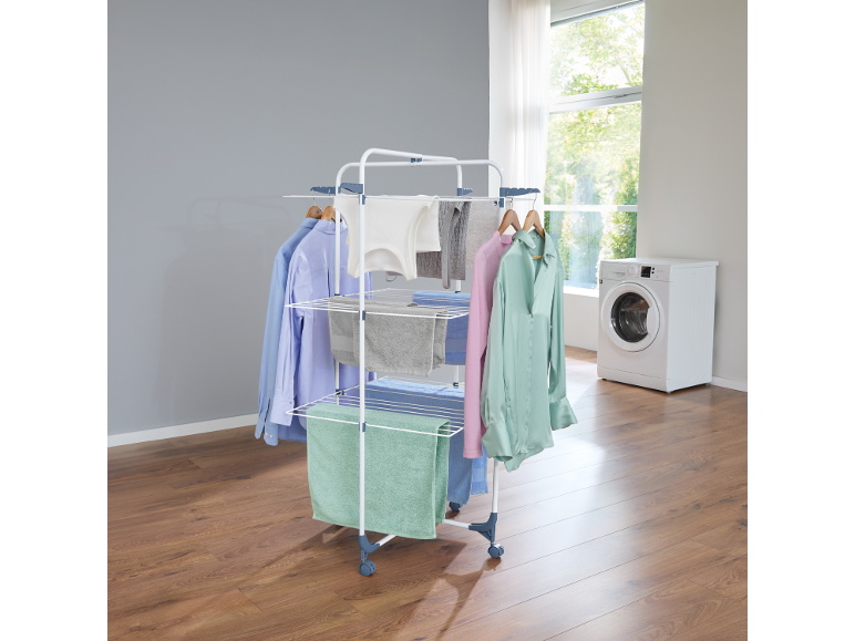 Clothes drying rack with laundry in a bright utility room.