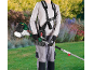 Man with harness and brush cutter in hands in a garden.