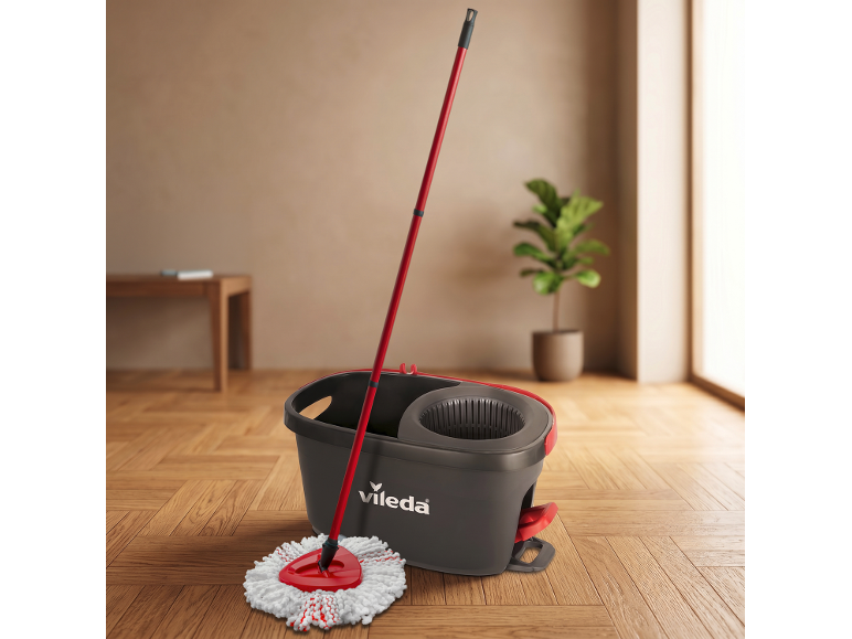 Red mop and grey bucket on the floor, with a houseplant in the background.