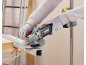 Person cutting a metal profile with a cordless angle grinder, generating sparks.