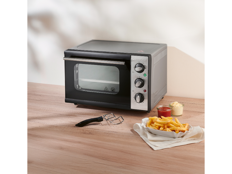 Mini oven with fries and sauces on a wooden table.