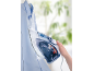 Steam iron ironing a blue shirt, held in hand.