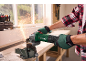 Man in gloves cuts metal with an angle grinder, sparks flying in a workshop.