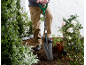 Person planting flowers with a shovel in a landscaped garden.