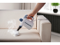 Handheld steam cleaner cleaning a cream sofa, with steam visible.