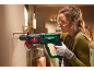 Woman in safety glasses and gloves drilling a wall with a rotary hammer.