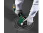 Man with gloved hands uses a tile vibrator on dark tiles.