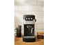 Black and silver espresso machine with stacked cups and coffee beans in a jar.