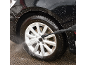 Washing black car with pressure washer, with foam and splashing water.