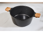 Black cooking pot with wooden handles and measurement markings on a white surface.