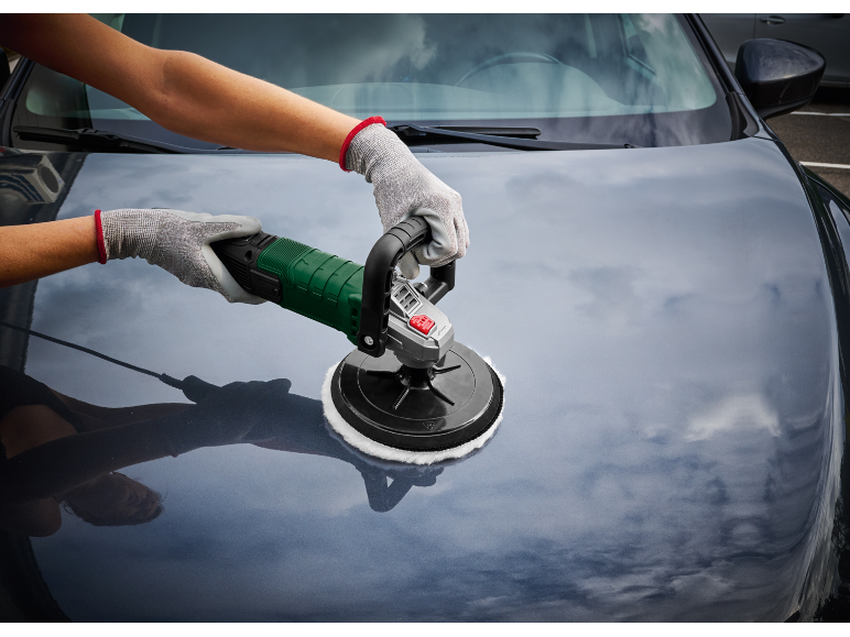 Gloved hands polishing a car hood with an electric polisher.