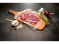 Vacuum-sealed steak on a board with garlic, rosemary, and onion.