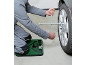Man changing a car wheel using a cross wrench and a kneeling pad.
