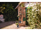 Gardening tools hanging on a wooden door, with a shovel and rake in the foreground.