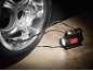 Portable tire inflator with a built-in light connected to a car tire.