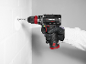 Cordless drill in hand, drilling into a white wall.