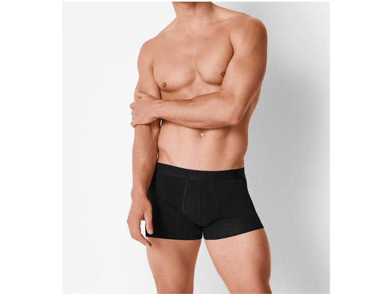 Shirtless man in black boxer briefs, arm crossed.