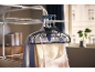 Clothes on hangers, hanging on a clothes drying rack in a bright room.