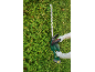 Person trimming a hedge with a cordless hedge trimmer.