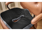 Black and grey orthopedic seat cushion on a brown leather chair.