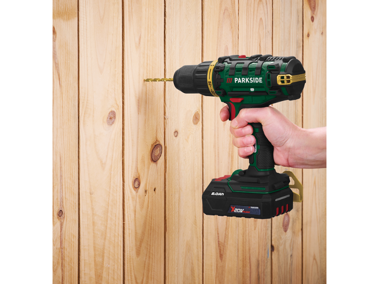 Cordless drill in hand, drilling into a wooden wall.