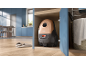 Compact vacuum cleaner in a wooden cabinet, with slippers on the floor of a modern kitchen.