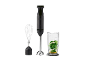 Black hand blender with whisk attachment and measuring cup with green ingredients.