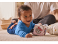 Happy baby in blue romper playing with a soft activity cube on the carpet.