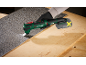 Cordless multi-tool cutting floor covering on a wooden workbench.