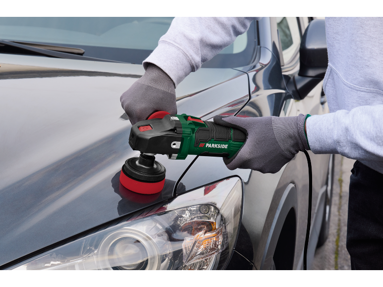 Person polishing a dark grey car with an electric car polisher.