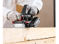 Gloved person using an electric planer on a wooden board.