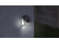 Solar-powered outdoor wall light illuminating a dark wall.