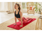 Woman in black sports bra and patterned leggings doing yoga on a red mat.