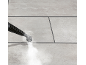 Steam cleaner nozzle cleaning light grey tiled floor with steam.