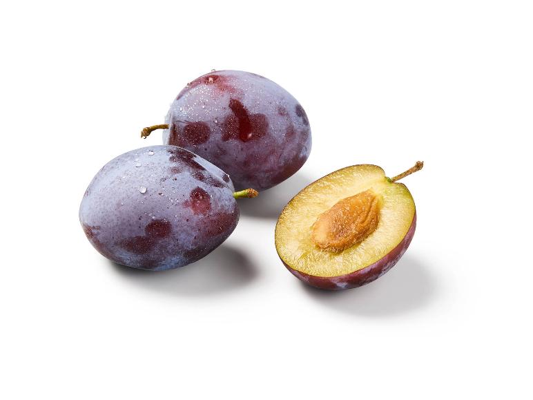 Two fresh plums and one halved plum with a visible pit on a white background.