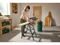 Woman using a circular saw and industrial vacuum cleaner to cut wood on a workbench.