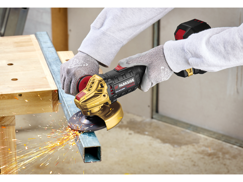 Worker cutting metal profile with a cordless angle grinder, sparks flying.