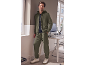 Man in olive green tracksuit set and sneakers, leaning against a wall.