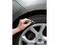 A hand marks a car tire with a white marker.