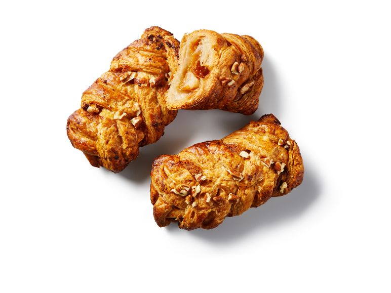 Two apple and pecan croissants, one cut in half, on a white background.