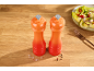 Orange salt and pepper grinders on a wooden table with a salad.