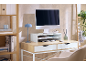 Home office desk with a computer, monitor stand, blue lamp, and wooden shelving.