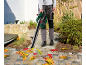 Man using a leaf blower to clear autumn leaves from a cobblestone path.