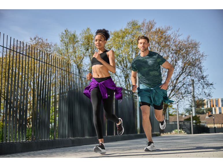 Two runners in athletic wear, jogging outdoors on a sunny day.