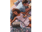 Couple in bed with floral bedding, woman with laptop and coffee, man reading a book.